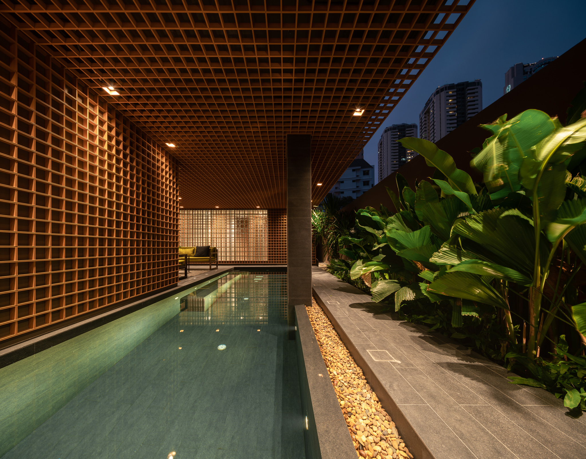 Outdoor pool with tropical plants and wooden lattice at twilight